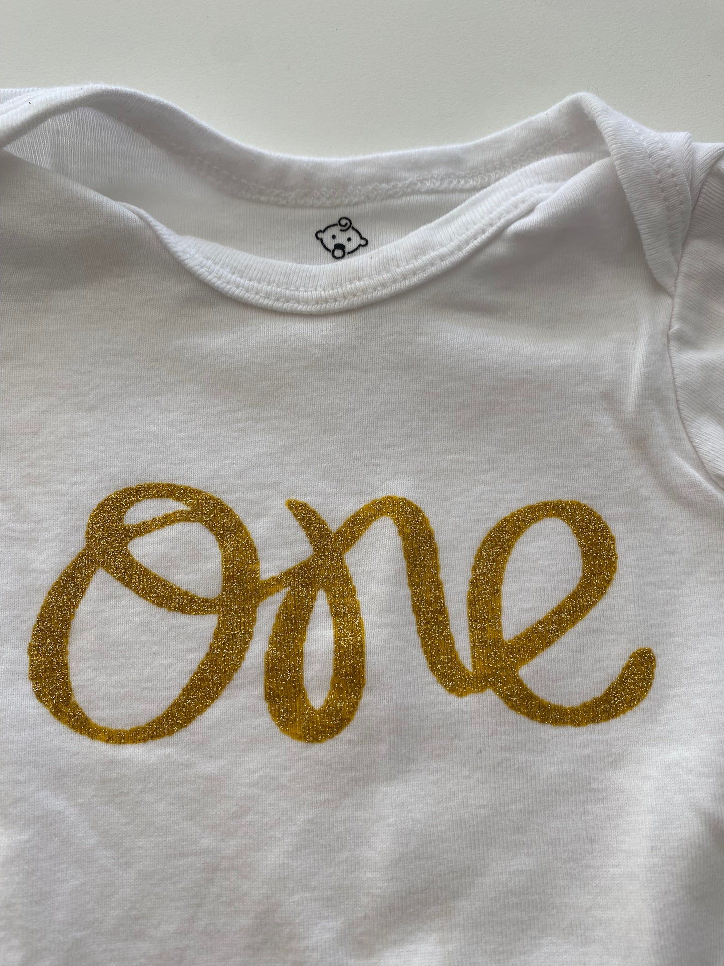 #117, 1st birthday white onesie w/ gold ‘one’ print, Girls 12M