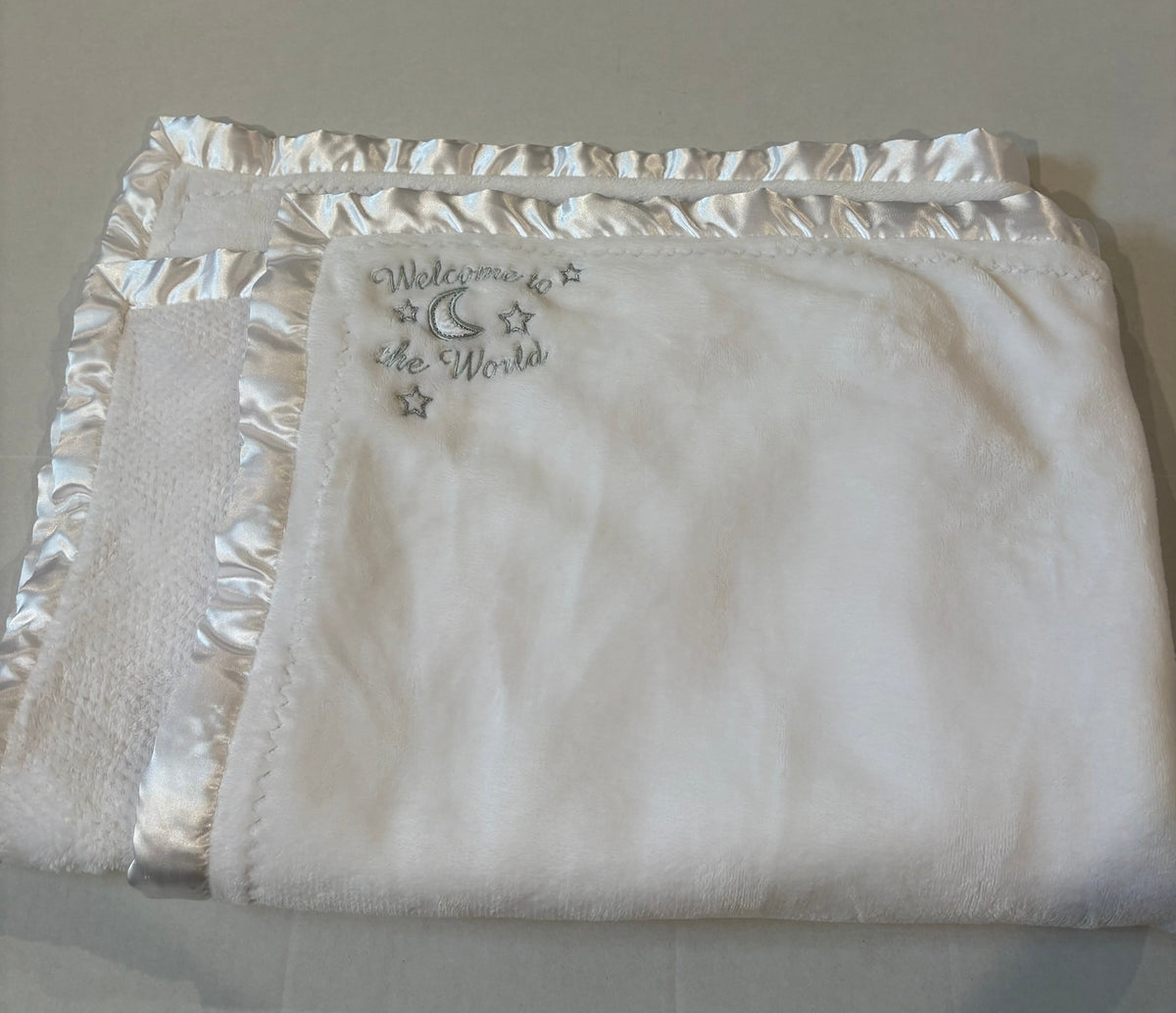 #25 White baby blanket that says “welcome to the world”