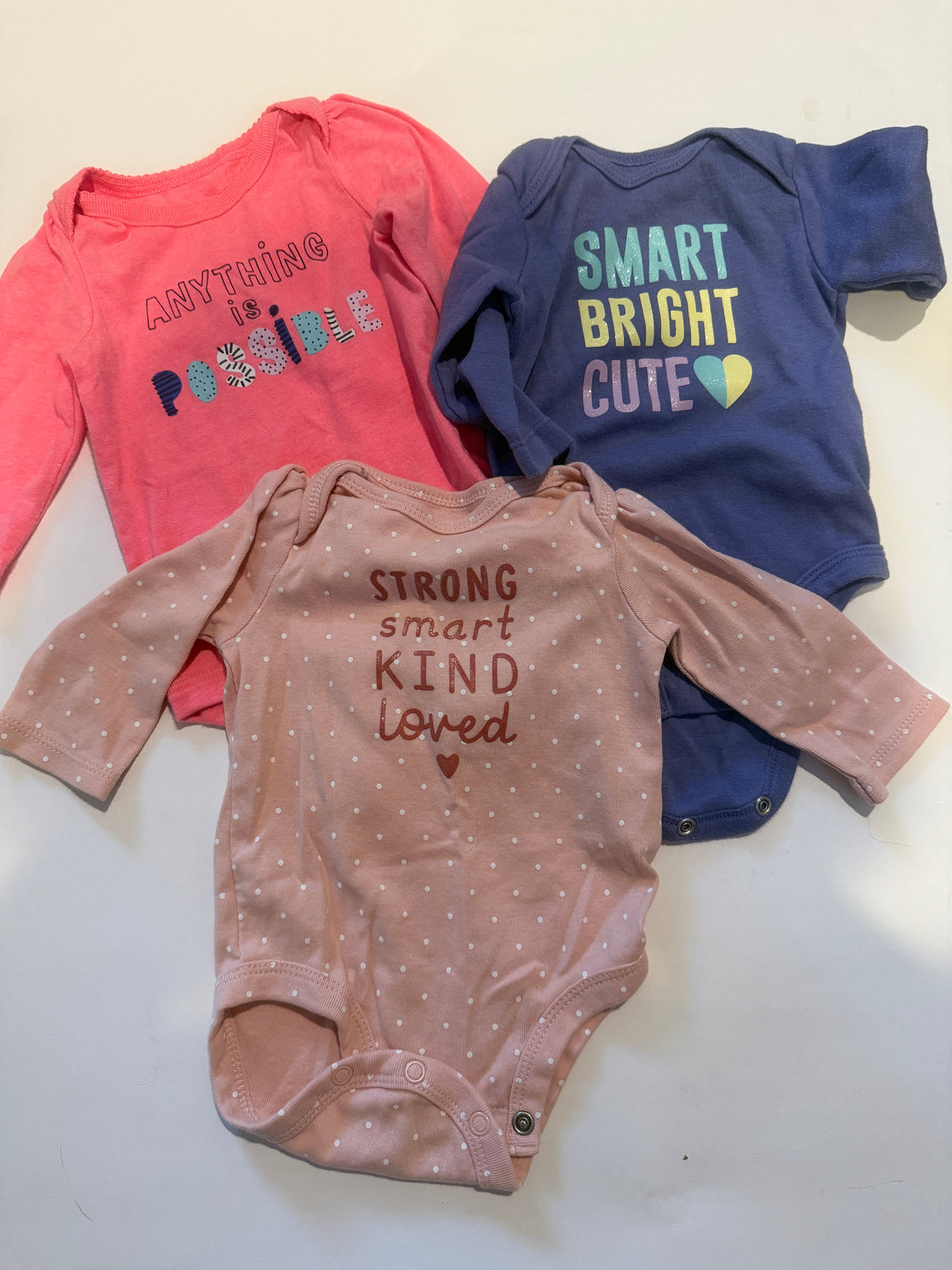 #170 Carters body suit bundle (3)— light pink polka dots with “Strong Smart kind Loved”, coral with “Anything is Possible and purple with “smart bright cute” girls 3 months
